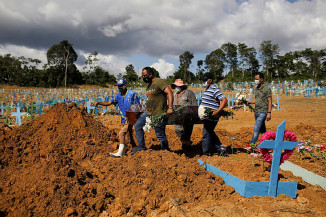 Filhos de Verônica Ferreira, de 73 anos, que morreu de Covid-19, vão a enterro da mãe em um cemitério de Manaus no dia 31 de dezembro. — Foto: Bruno Kelly/Reuters