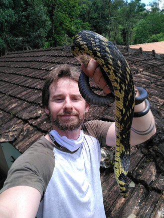 O biólogo Christian Raboch e a caninana resgatada no telhado — Foto: Christian Raboch/Arquivo Pessoal